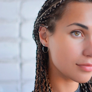 Close-up of minimalist silver hoop earrings on a fashion model with braided hair style