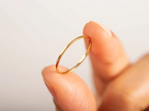Macro shot of minimalist slim gold-plated stainless steel band on a finger