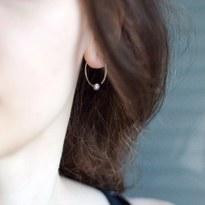 Close-up of minimalist silver hoop earring with small cubic zirconia on a female model