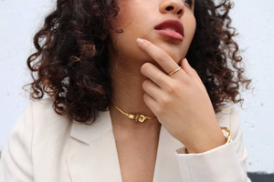Close-up of minimalist gold plated jewelry set featuring ring, necklace and cuff bracelet