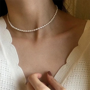 Élégant collier en acier inoxydable avec petites perles blanches ovales sur un mannequin