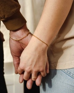 Close-up of gold-plated stainless steel curb chain bracelets and minimalist ring on model