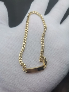 Detailed macro view of a gold-plated stainless steel Cuban link ID bracelet with flat plate