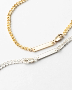Close-up of polished gold and silver Cuban chain bracelets with rectangle pendants