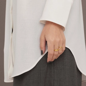 Polished gold minimalist stackable stainless steel rings set worn by a model