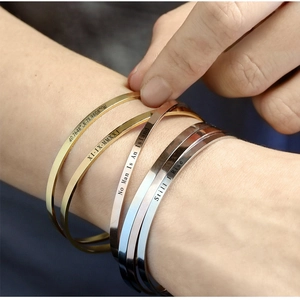 Macro detail of custom engraved coordinates and text on stainless steel cuff bracelets