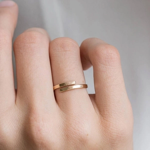 Dettaglio anello aperto dorato minimalista con trama martellata sulla mano