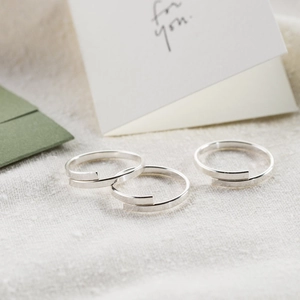 Set di tre anelli aperti minimalisti in argento presentati su un elegante biglietto regalo