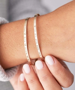Close-up of gold-plated stainless steel cuff with custom laser engraving on model wrist