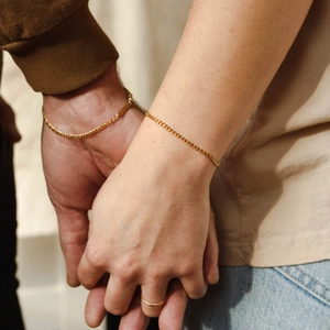Minimalist gold plated stainless steel Cuban chain bracelet and ring set worn by a couple