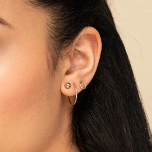 Three-piece set of geometric 316L stainless steel gold earrings on a female ear model