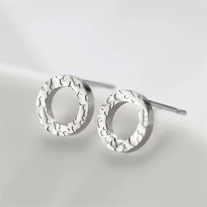 Macro shot of silver textured hoop earrings with hammered finish on white background