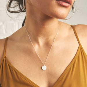 Gros plan d'un collier avec pendentif rond argenté minimaliste sur un mannequin