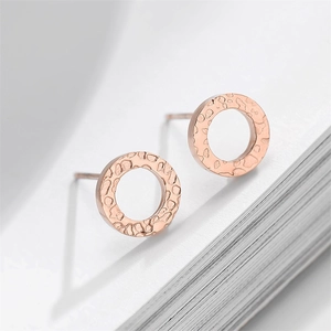 Macro shot of rose gold titanium earrings with hammer-textured finish and donut shape