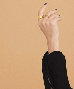Close-up of a gold rectangle signet ring and layered bands worn on a hand