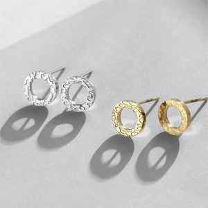 Macro view of geometric round stud earrings with hammered texture in gold and silver finish