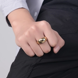 Gros plan détaillé d'une bague bombée dorée polie miroir portée au doigt d'une personne