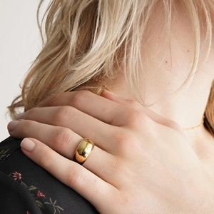 Gros plan d'une large bague en acier titane doré poli portée par un mannequin