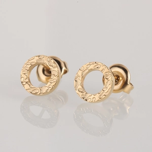 Close-up of golden geometric stud earrings with textured hammered finish on circular design