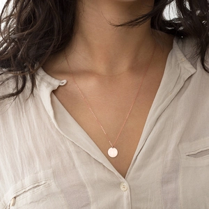Collier minimaliste en or rose avec pendentif rond porté élégamment sur le cou