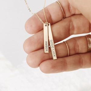 Detail of gold rectangular pendant necklace with Amber and Good Luck engravings