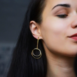 Close-up of model wearing gold and silver nested hoop earrings with fine metal chains