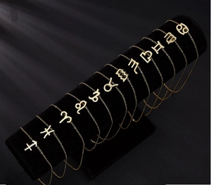 Détail de 12 bracelets zodiacaux plaqués or présentés sur un support en velours noir