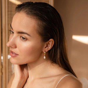 Detail of 14K gold plated stainless steel hoop earring with freshwater pearl on a model