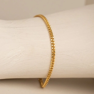 Close-up of a 14k gold-plated stainless steel curb chain bracelet on a white display