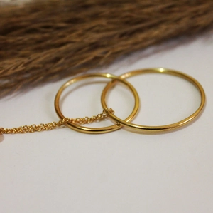 Detailed view of connected gold hoop earrings with minimalist polished finish and fine chain