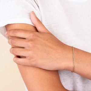 Detail of a minimalist 14k gold plated Cuban link bracelet on a woman's wrist