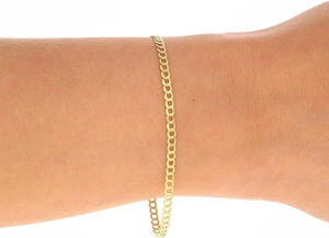 Close-up of a 14k gold-plated stainless steel curb link bracelet worn on a female wrist
