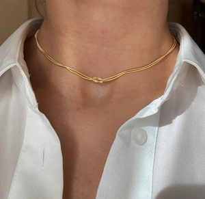 Vue détaillée d'un collier chaîne serpent double rang doré avec un design de nœud central