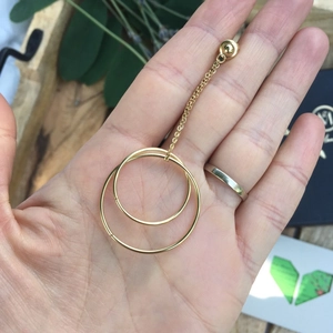 Detail view of gold geometric concentric circle earrings with delicate chain on a palm