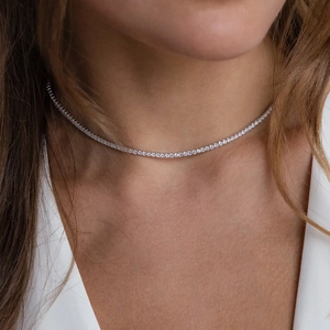 Close-up of thin sparkling tennis necklace with round cubic zirconia on female model