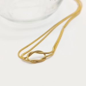 Vue rapprochée du collier chaîne serpent dorée avec un nœud et texture polie