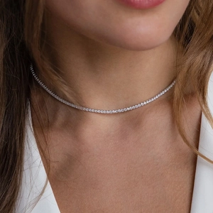 Close-up of a silver tennis necklace with round brilliant-cut zircons on a model's neck