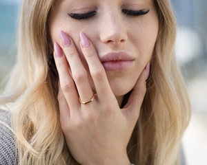 Minimalist gold geometric rectangular ring displayed on a female hand in a soft outdoor light