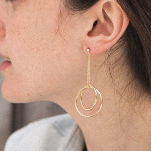 Gold stainless steel long drop earrings with minimalist concentric circles on female model