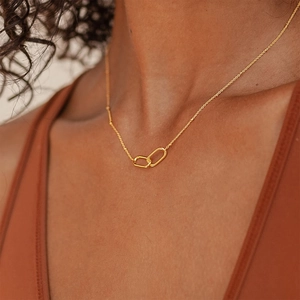 Close-up of minimalist gold interlocking rectangular links necklace worn by a model