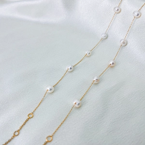 Detail of delicate pearl bracelet with gold chain on elegant white silk background