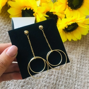 Detailed macro view of gold-tone geometric double circle drop earrings on display card