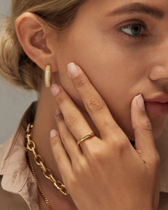 Close-up of minimalist 18K gold ring, chain necklace and pavé hoop earrings on model