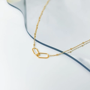 Minimalist gold necklace featuring interlocking oval paperclip links on a beaded chain