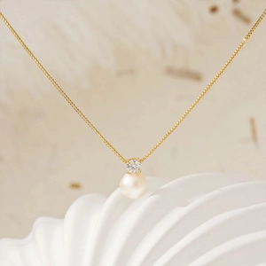 Elegant gold stainless steel necklace with pearl and zircon pendant on wave prop