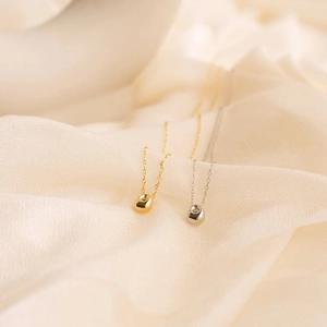 Close-up of minimalist gold and silver teardrop pendants with sparkling zircon stones