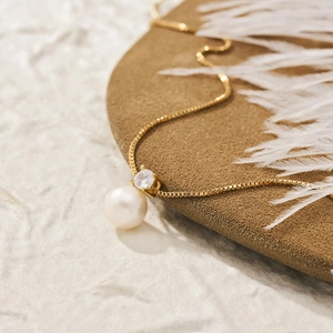 Elegant gold pearl necklace with zircon pendant on a luxury minimalist display