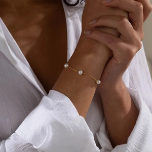 Elegant gold chain bracelet with three minimalist pearls on a female wrist