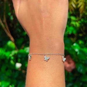 Bracelet papillon argenté étincelant serti de zircons porté au poignet d'une femme