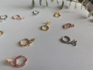 Detail of butterfly hoop earrings in gold, silver and rose gold with zircon inlay